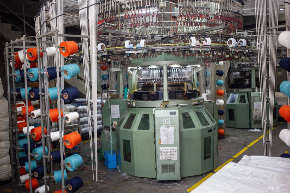 Circular knitting machine number 93, a green Fukuhara unit, surrounded by creels of orange, blue and white yarn.