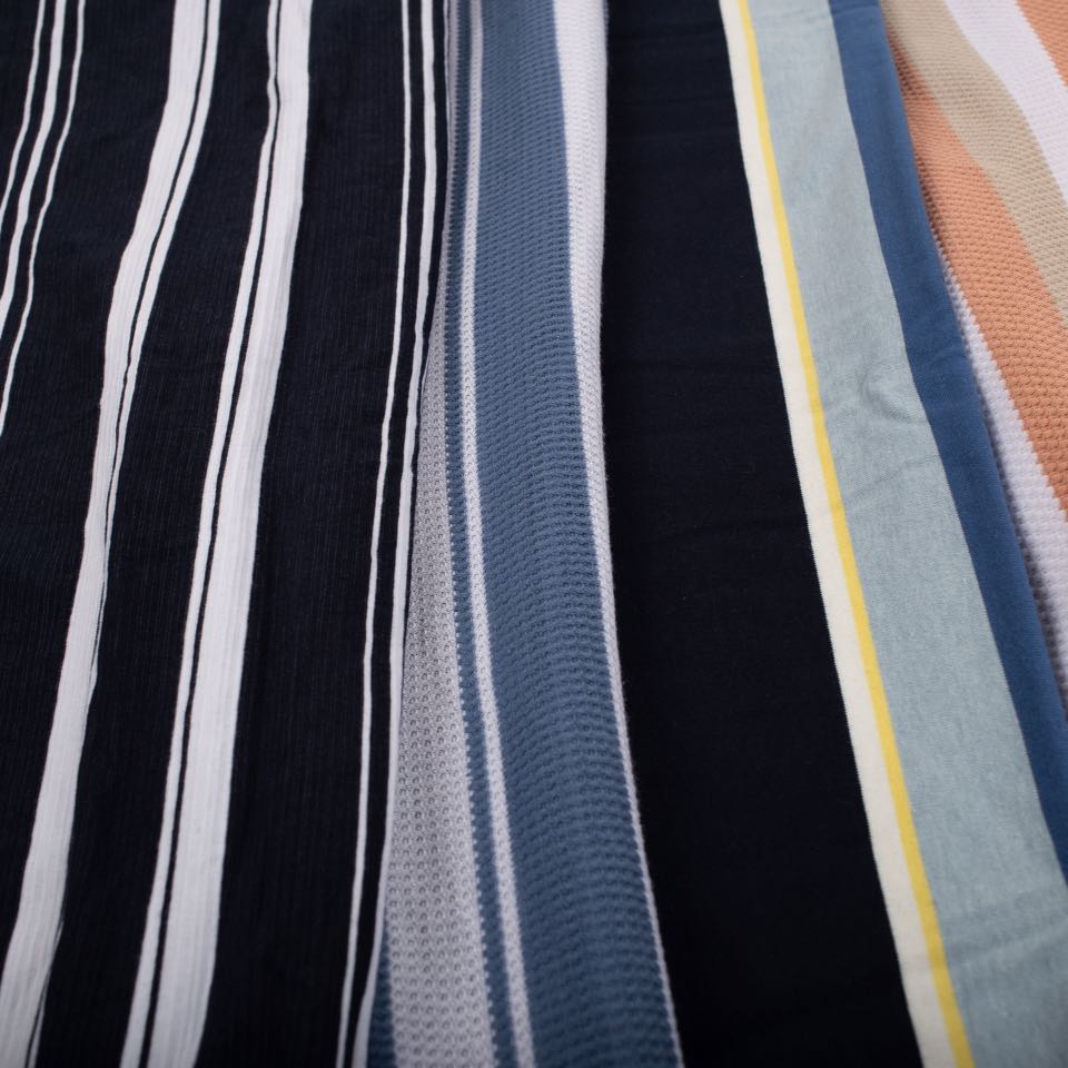 Auto-stripe knit running from black and white pinstripes through blue and yellow bands to peach and sand.