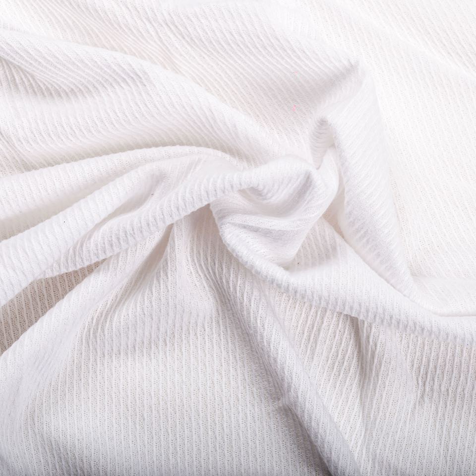 White knitted fabric with raised vertical ribs, gathered into soft folds.