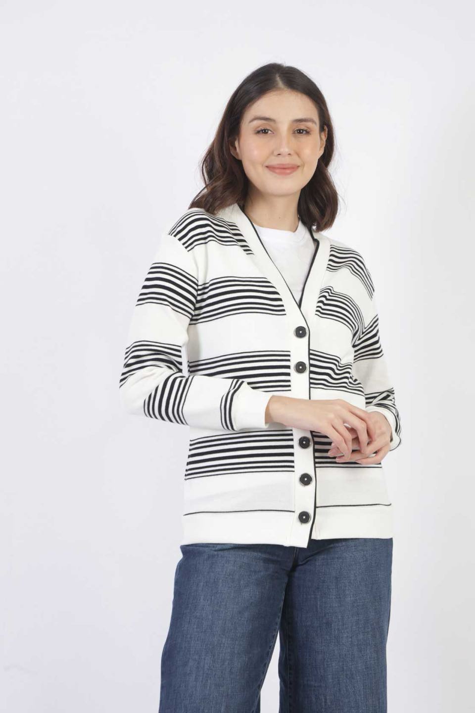 A woman in a white striped knit cardigan with black buttons, worn over wide-leg jeans.